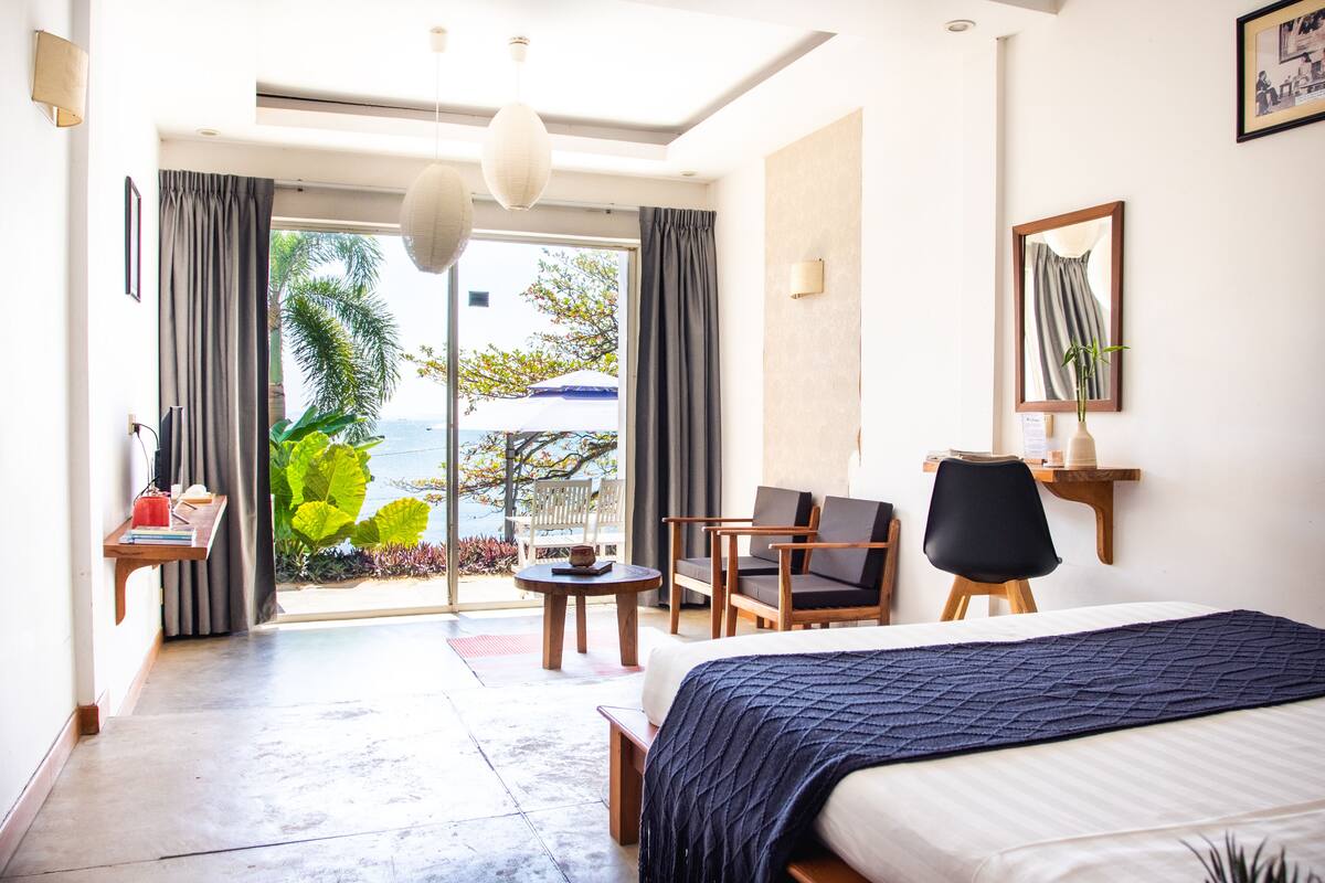 A hotel room with a bed, a desk, a chair, and a view of the outdoors.