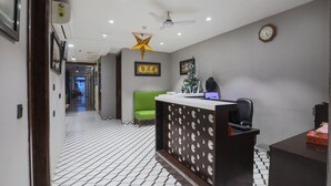 A reception area with a reception desk, a green sofa, a decorative star hanging from the ceiling, and a clock on the wall. - Hotel BlueStone - Nehru Place (New Delhi)