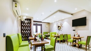 A restaurant with green chairs, wooden tables, and a tiled floor. - Hotel BlueStone - Nehru Place (New Delhi)