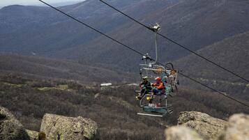 A cable car moving over a mountainous landscape with rocky terrain and sparse vegetation.