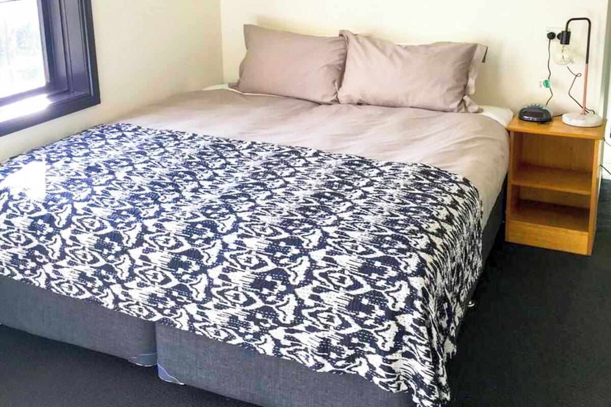 A bedroom with a bed, a nightstand, a lamp, and a framed picture on the wall.