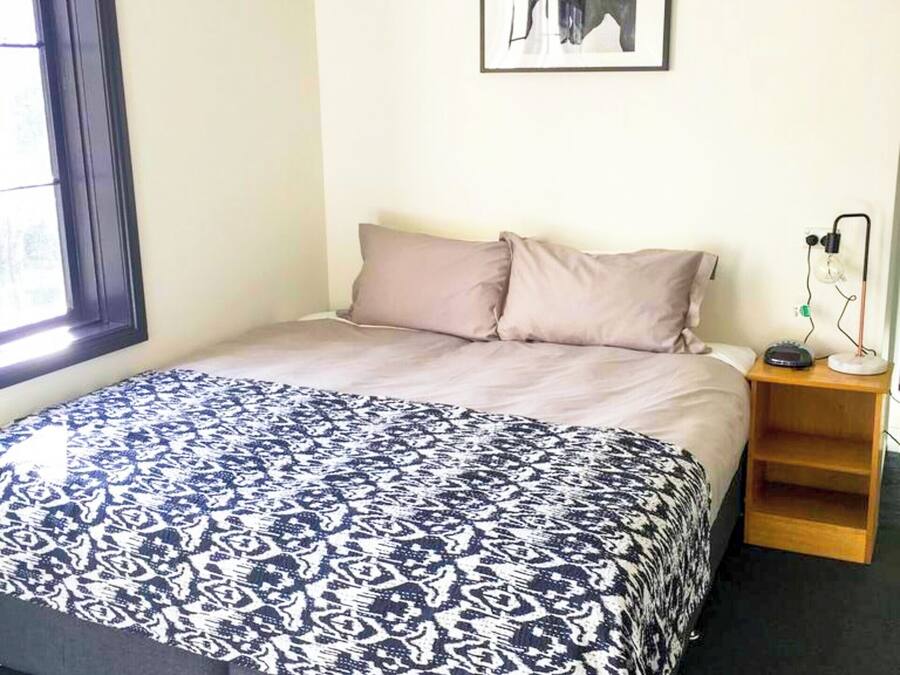 A bedroom with a bed, a nightstand, a lamp, and a framed picture on the wall.
