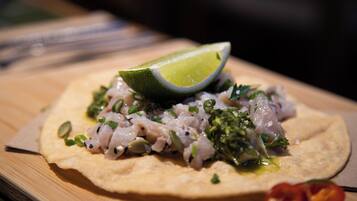 Una focaccia ricoperta di un piatto di pesce, guarnita con erbe aromatiche e una fetta di lime.