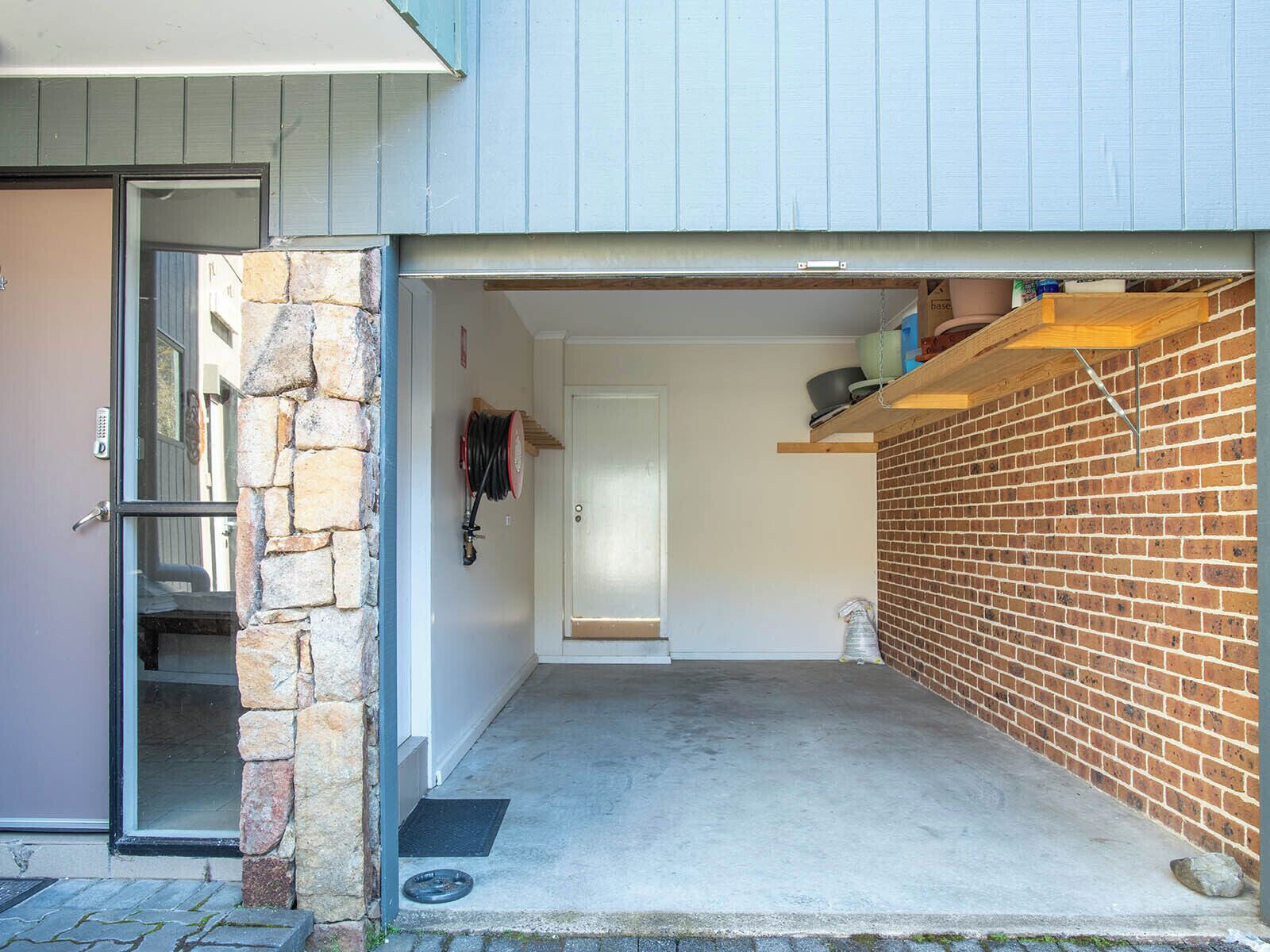 Un garage avec un mur en pierre, une porte et un sol en béton.