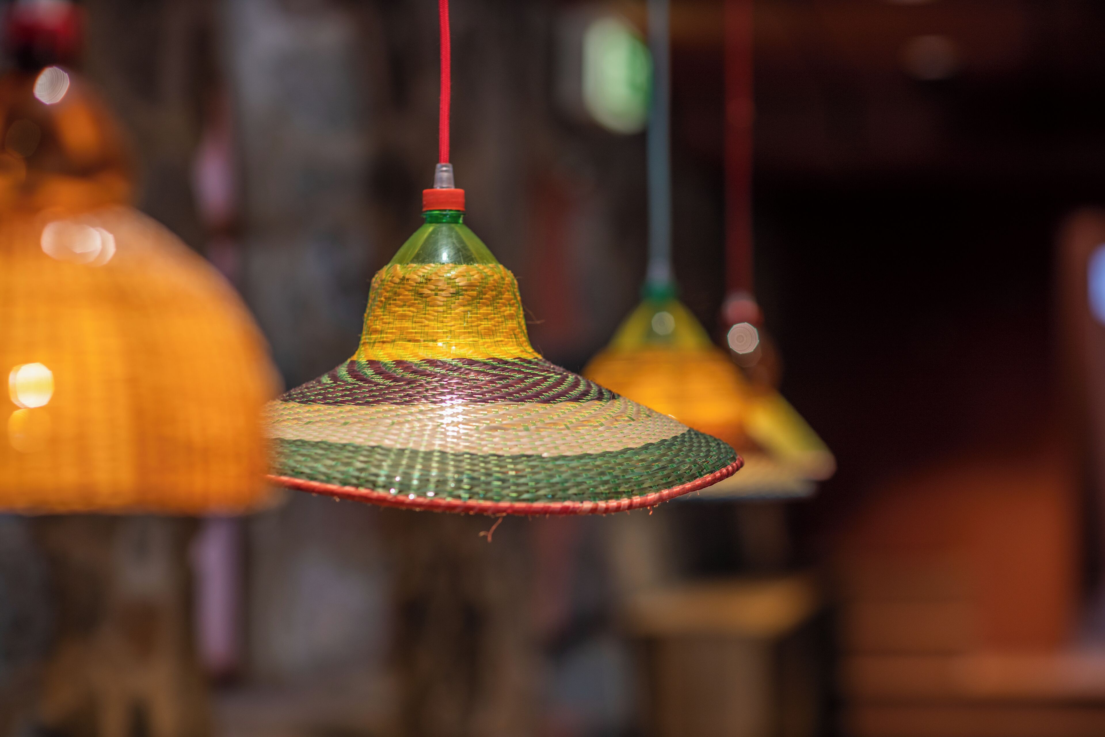 A close-up of a hanging lamp made from a plastic bottle with a woven base.