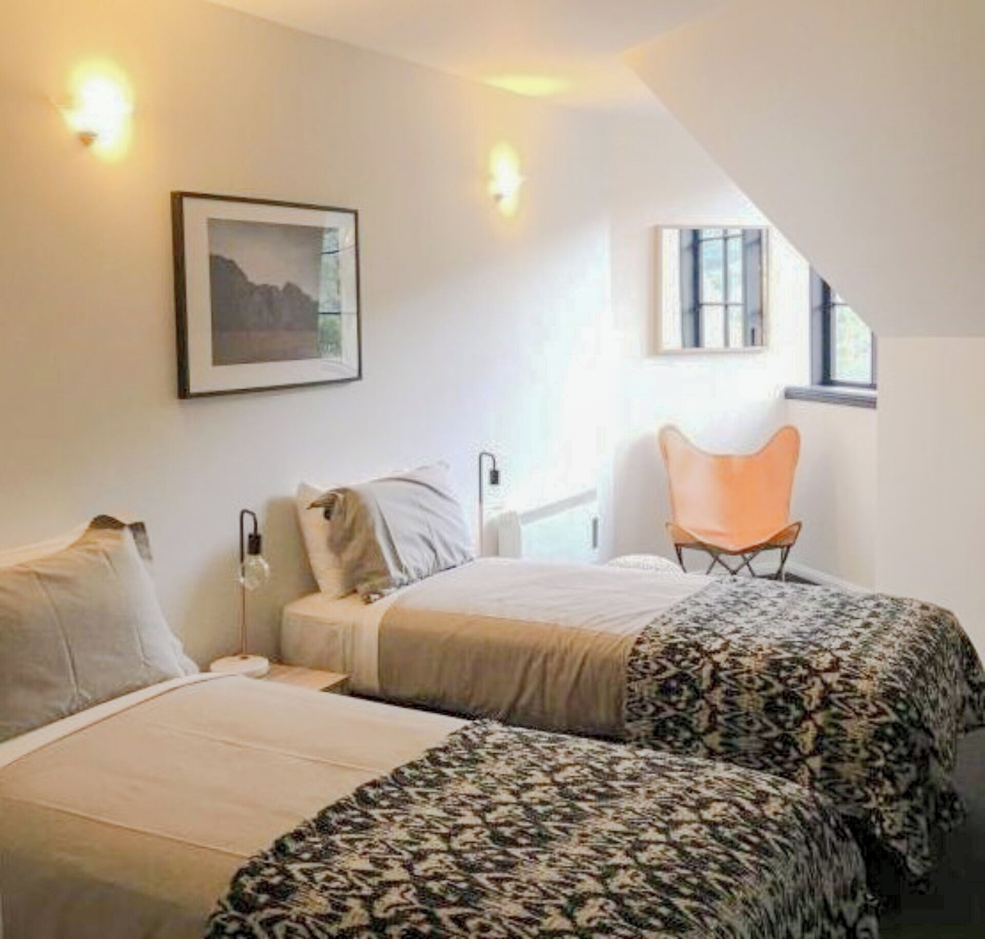 A bedroom with two beds, a chair, and a framed picture on the wall.