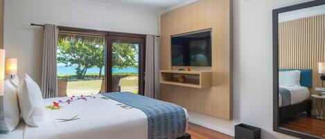 A hotel room with a bed, a TV, a large window with a view of the outdoors, and a mirror on the wall.