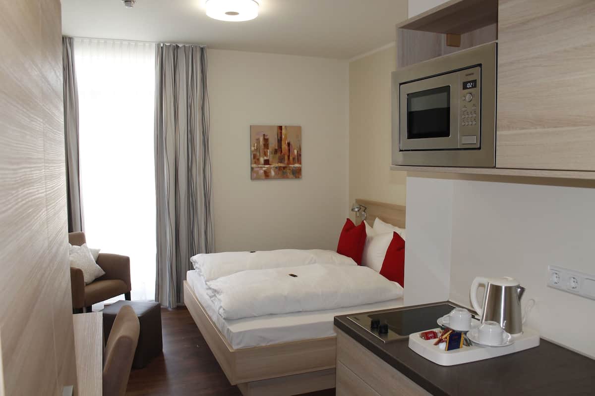 Une chambre d’hôtel équipée d’un lit, d’une chaise, d’un bureau avec une machine à café et d’un four à micro-ondes.