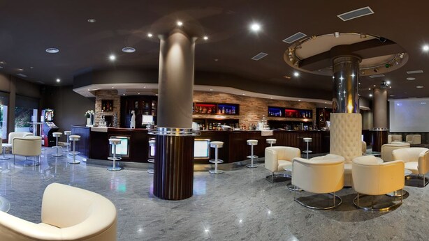 Un hall d’entrée moderne doté d’un bar, de coins salon et d’un grand écran.