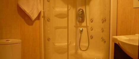 A bathroom with a glass-enclosed shower, a toilet, and a sink.