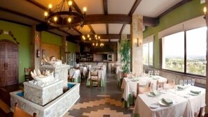 Un restaurant avec un plafond haut, des lustres et des tables dressées pour le dîner.