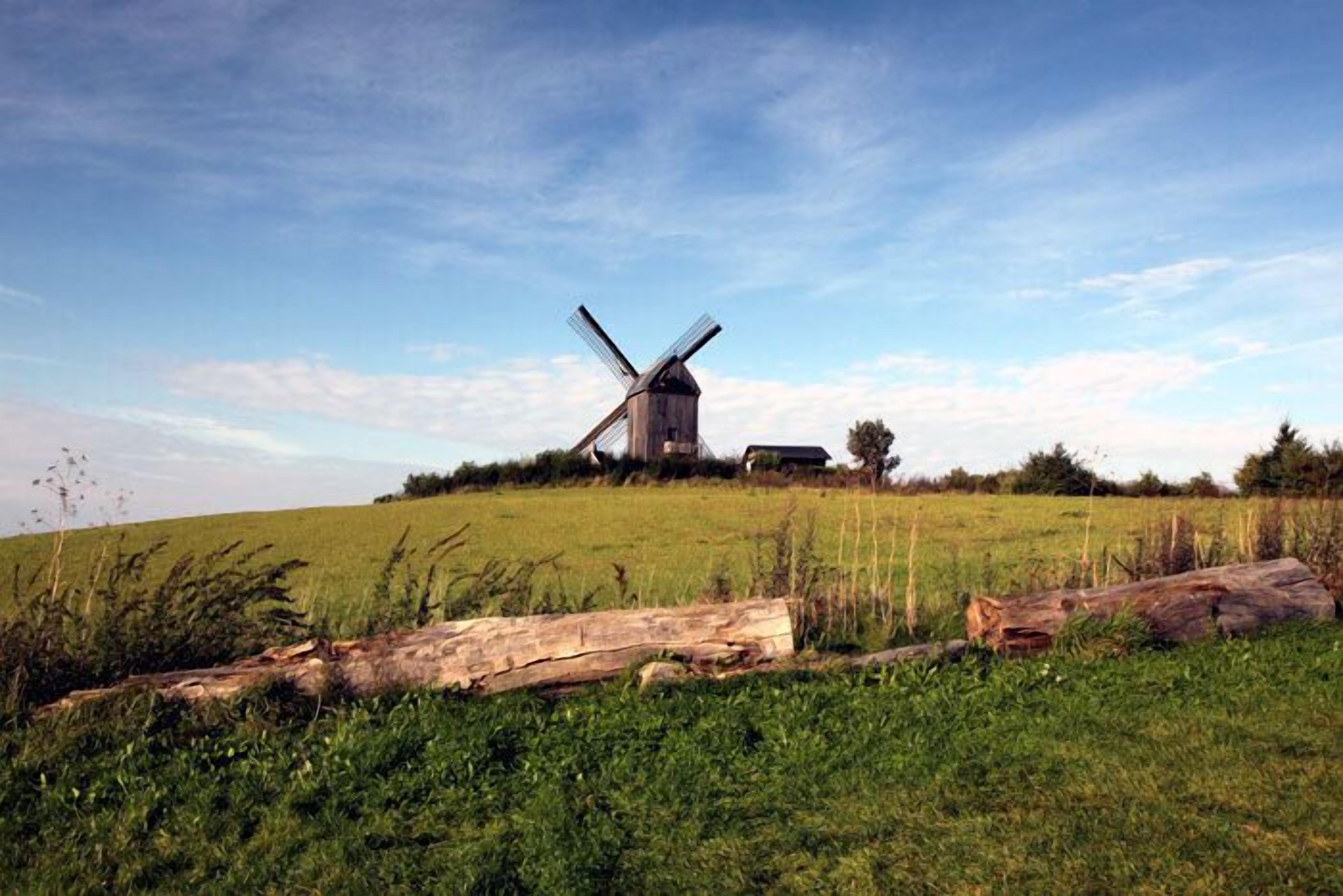A windmill on a grassy hill with a clear sky.