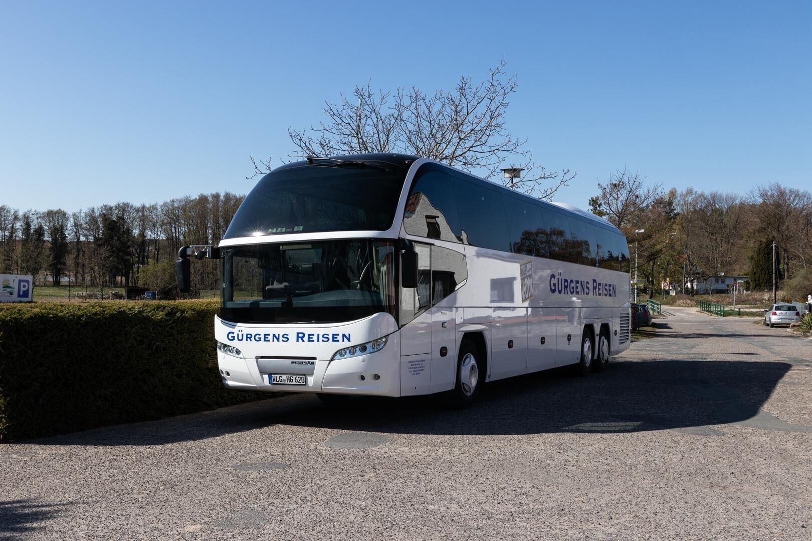 A large white bus with "Gürgens Reisen" on the side parked on a gravel road.