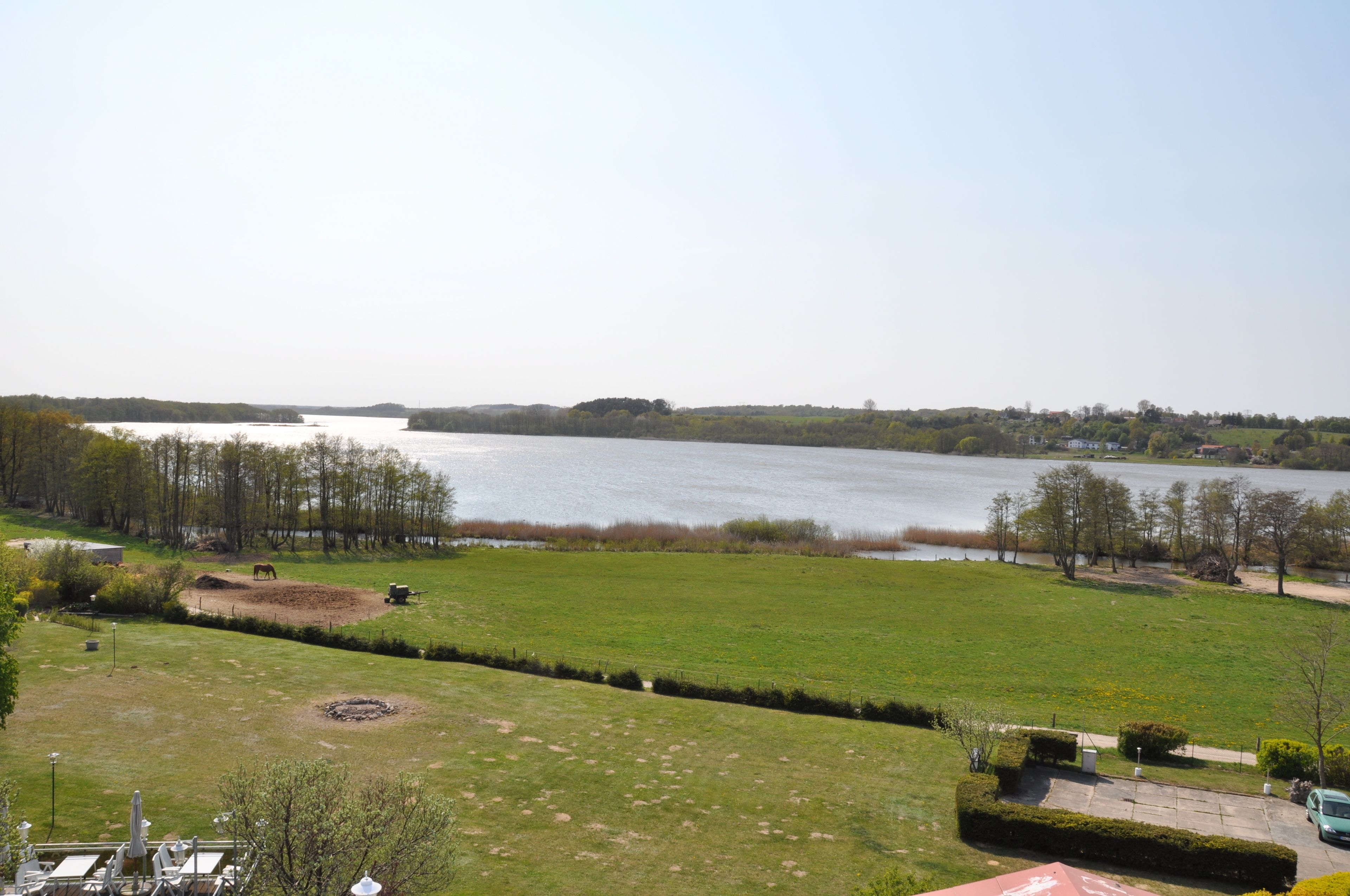 Vista de un lago con una zona cubierta de césped al frente y una orilla distante.