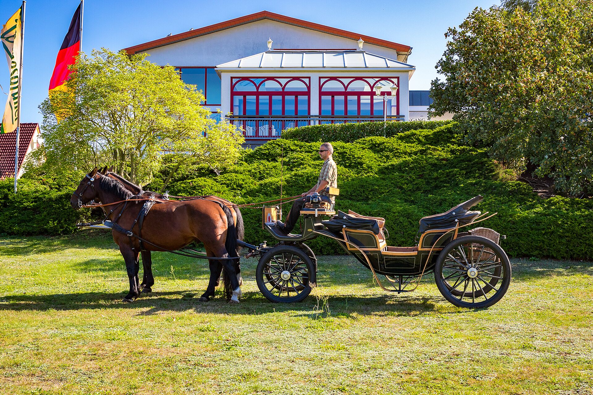 Une calèche tirée par des chevaux devant un bâtiment à la façade rouge et blanche.