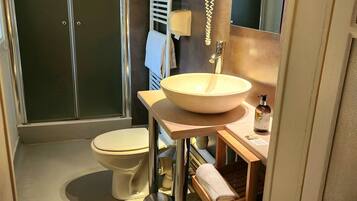 A modern bathroom with a glass shower enclosure, a toilet, a sink with a mirror, and a towel rack.