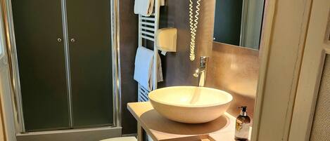 A modern bathroom with a glass shower enclosure, a toilet, a sink with a mirror, and a towel rack.