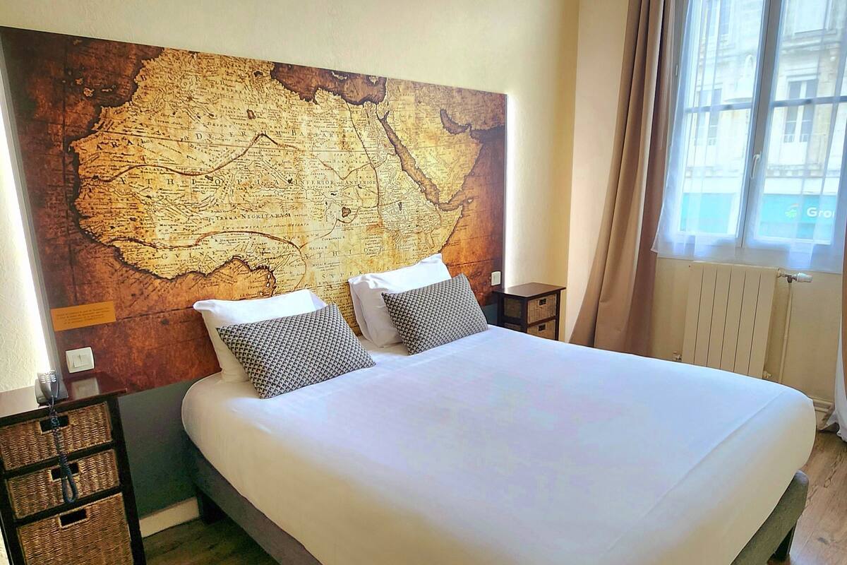 A large bed with white bedding, two pillows, and a wooden headboard.