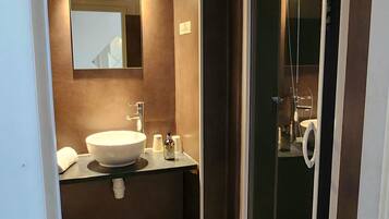 A modern bathroom with a large sink, mirror, and a glass shower enclosure.