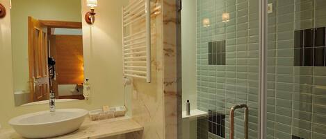 Un baño moderno con un lavamanos grande, un espejo y una zona de ducha con mampara de cristal.