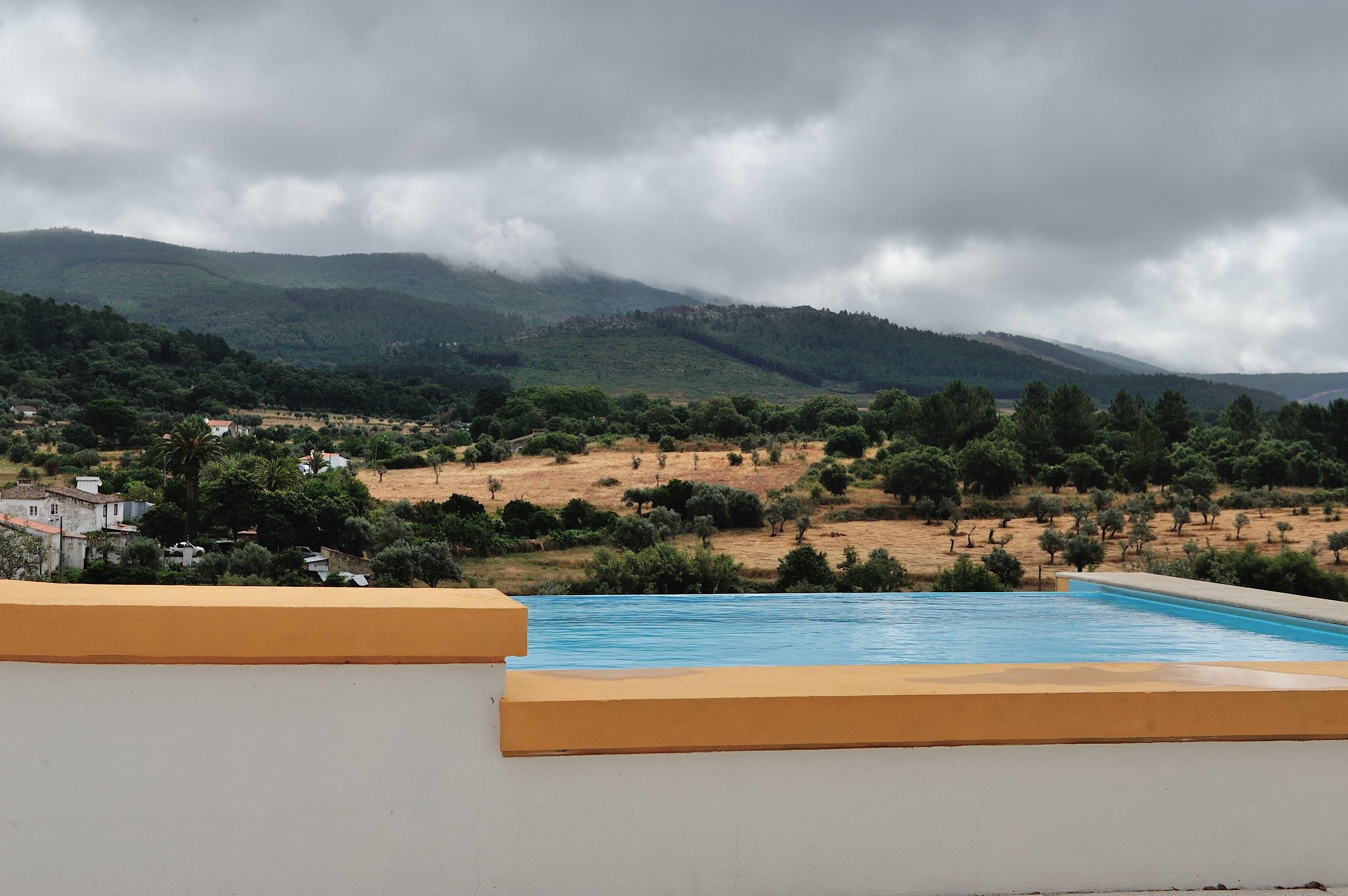 Una piscina con vistas a un paisaje montañoso y algunos edificios a lo lejos.