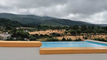 Una piscina con vistas a un paisaje montañoso y algunos edificios a lo lejos.