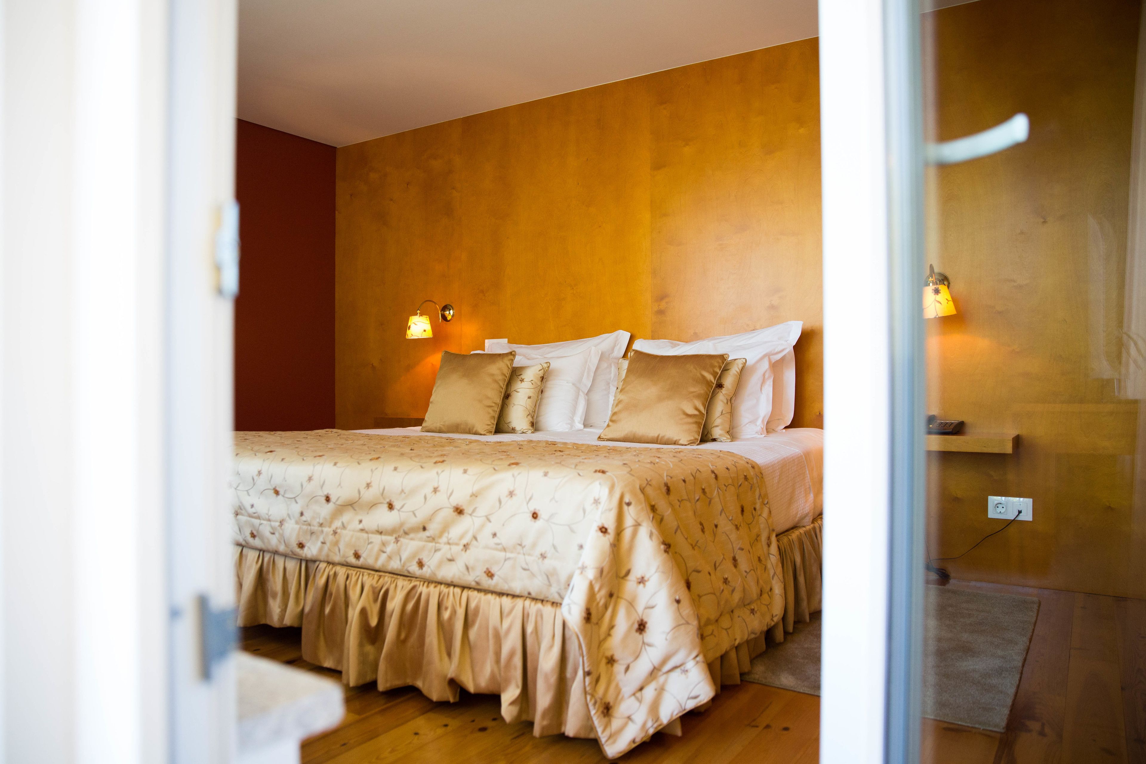 A bedroom with a large bed, two bedside lamps, and a wooden wall.