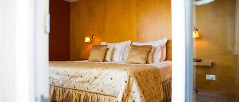 A bedroom with a large bed, two bedside lamps, and a wooden wall.