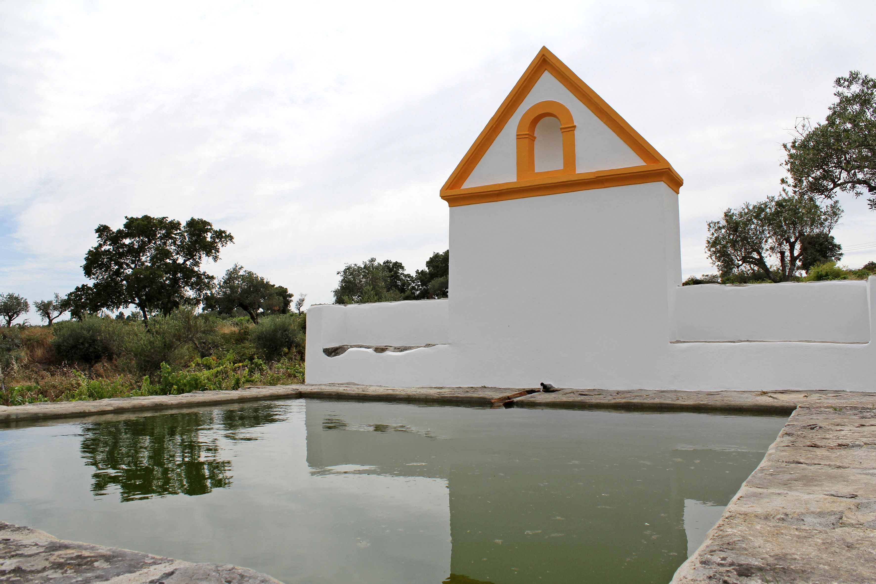 Un edificio blanco con techo triangular amarillo y un pequeño arco.