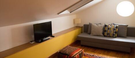 A cozy living room with a television, sofa, and patterned rug.