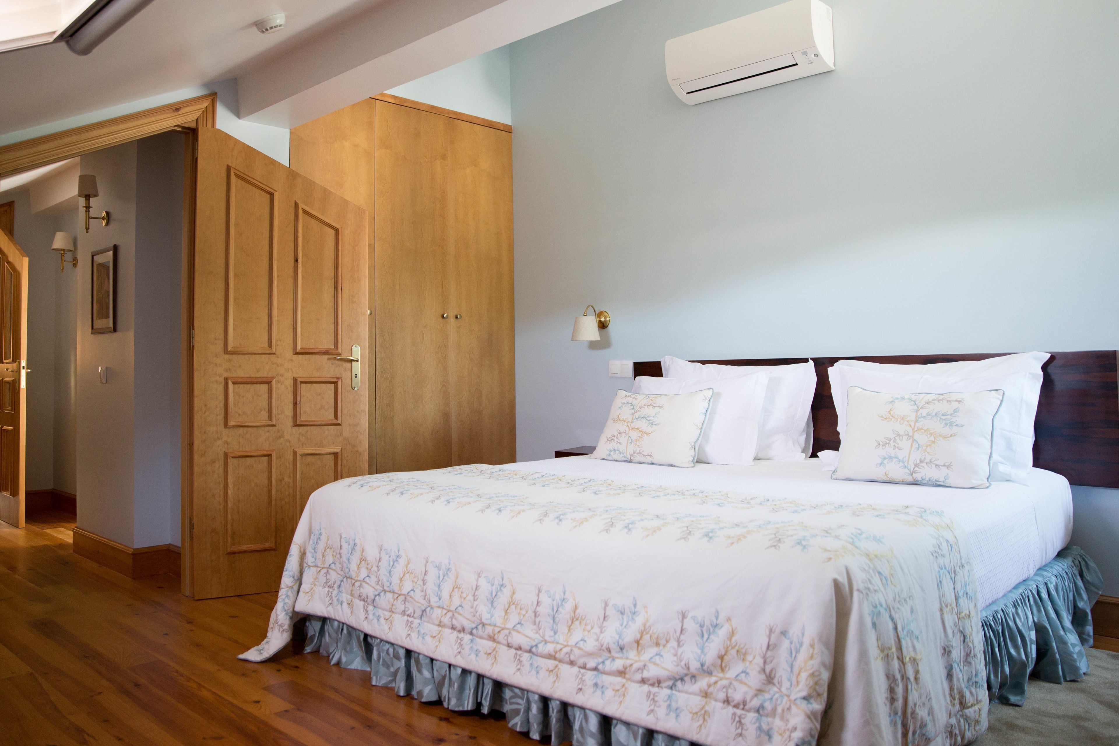 Un dormitorio con una cama grande, un armario de madera y un equipo de aire acondicionado en la pared.