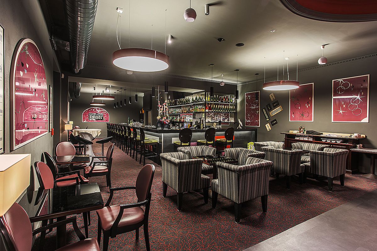 A bar area with seating, a bar counter, and shelves with bottles.