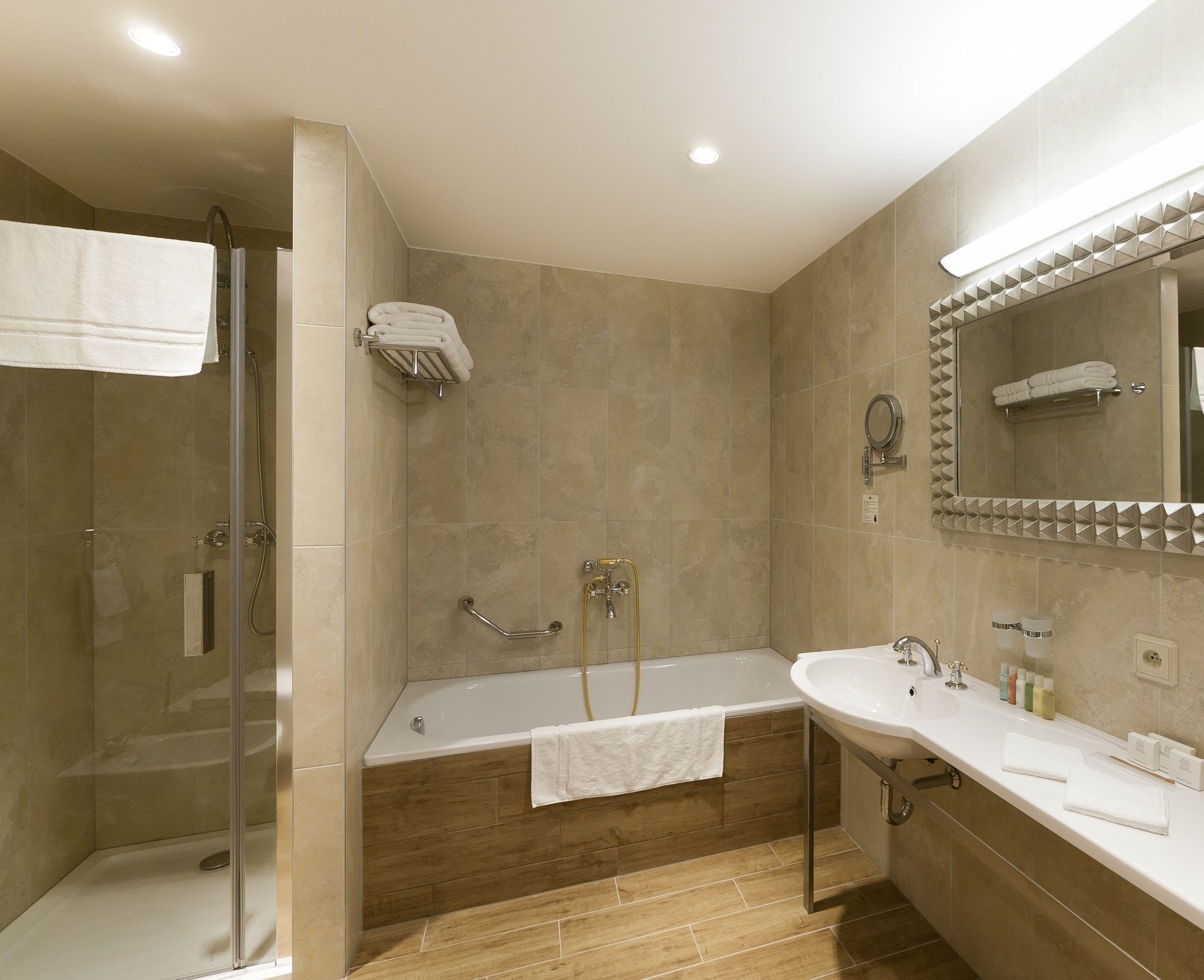 A modern bathroom with a glass-enclosed shower, a freestanding bathtub, and a vanity with a large mirror.