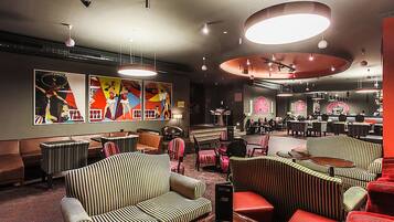 A modern lounge area with striped sofas, red chairs, and a bar area with stools.