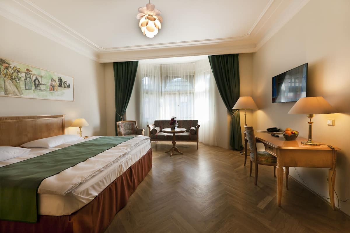 Een hotelkamer met een bed, een stoel, een tafel en een lamp.