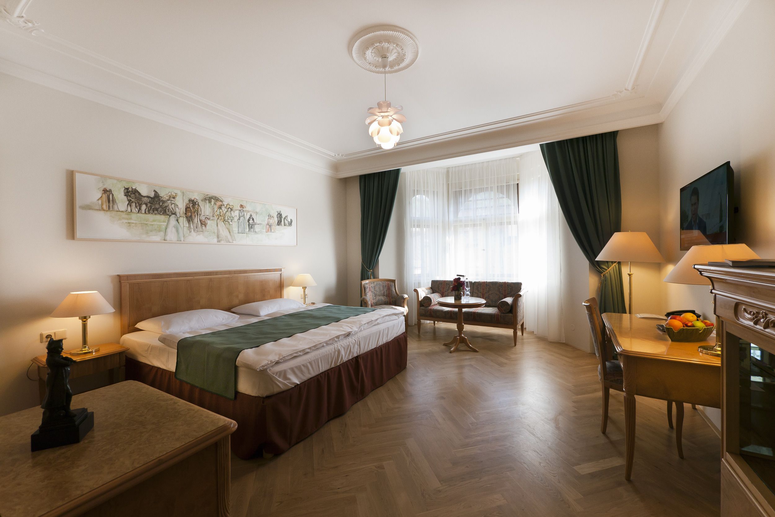 A hotel room with a bed, a desk, a chair, a table, and a painting on the wall.