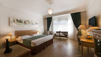 A hotel room with a bed, a desk, a chair, a table, and a painting on the wall.