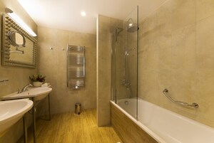 Un baño moderno con ducha envuelta en vidrio, una bañera independiente y un tocador con espejo y lavabo.