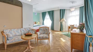 Una habitación de hotel con un conjunto de sofá, una pequeña mesa redonda, una cama, un escritorio y una lámpara.