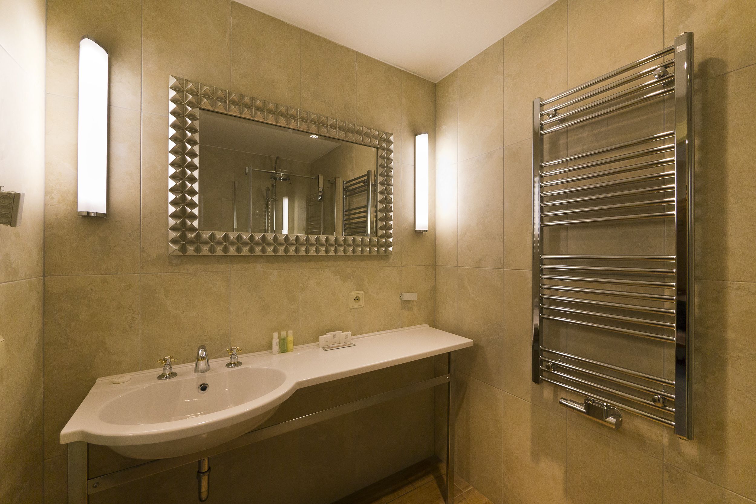 A modern bathroom with a large sink, a mirror with a geometric pattern, and a towel rack.