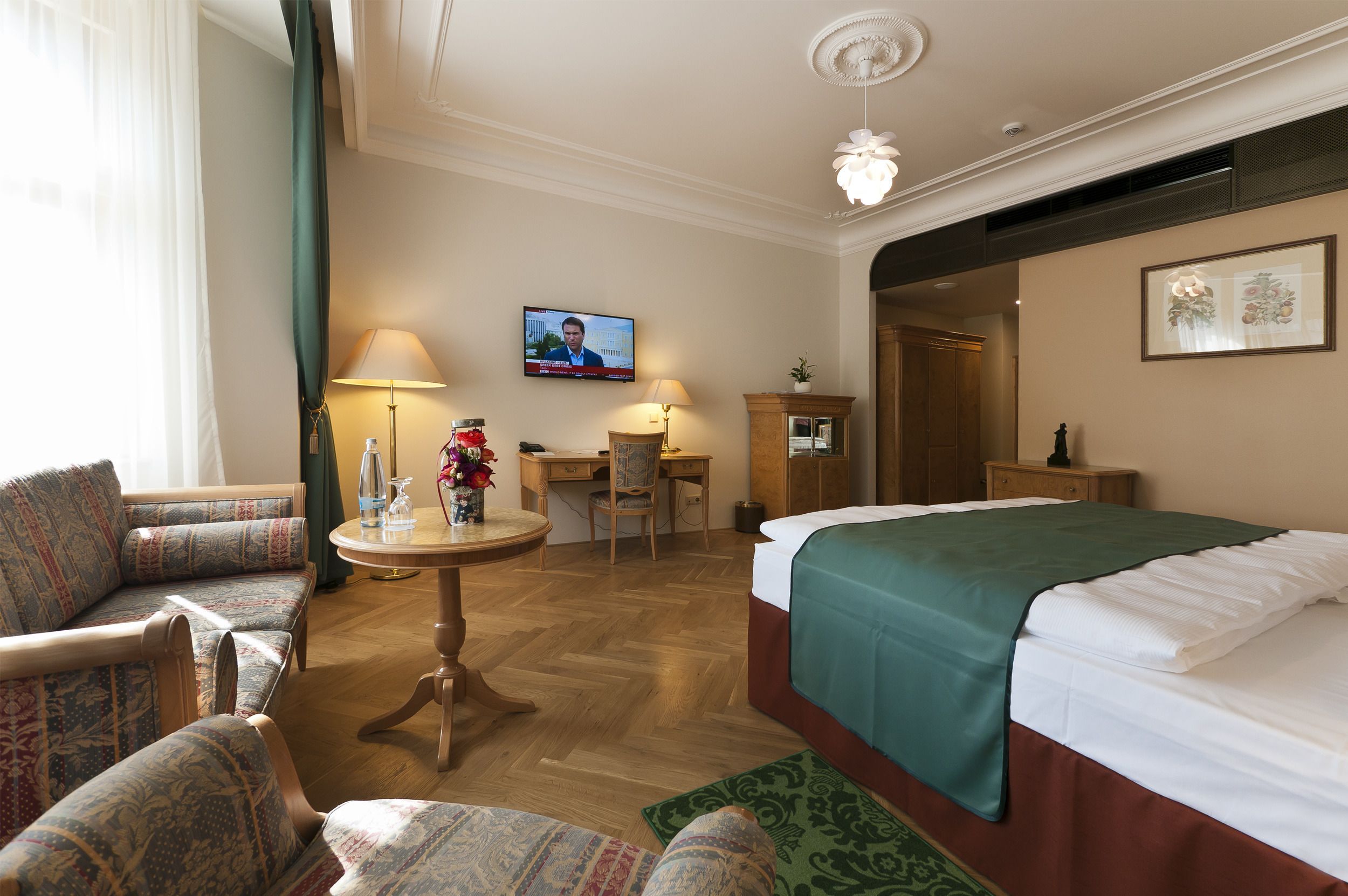 Een hotelkamer met een bed, een bureau, een stoel, een televisie en een bank.