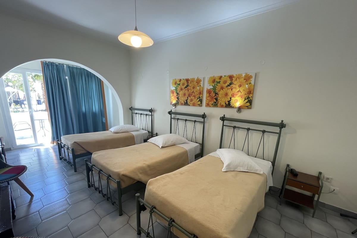 Una habitación con tres camas individuales, un escritorio pequeño y una silla.