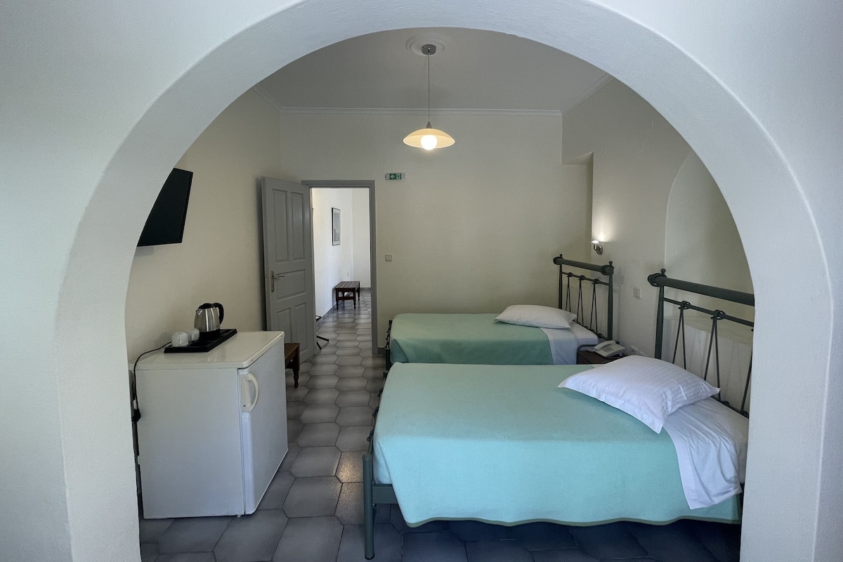 Una habitación pequeña con una cama, un escritorio y una mesita.