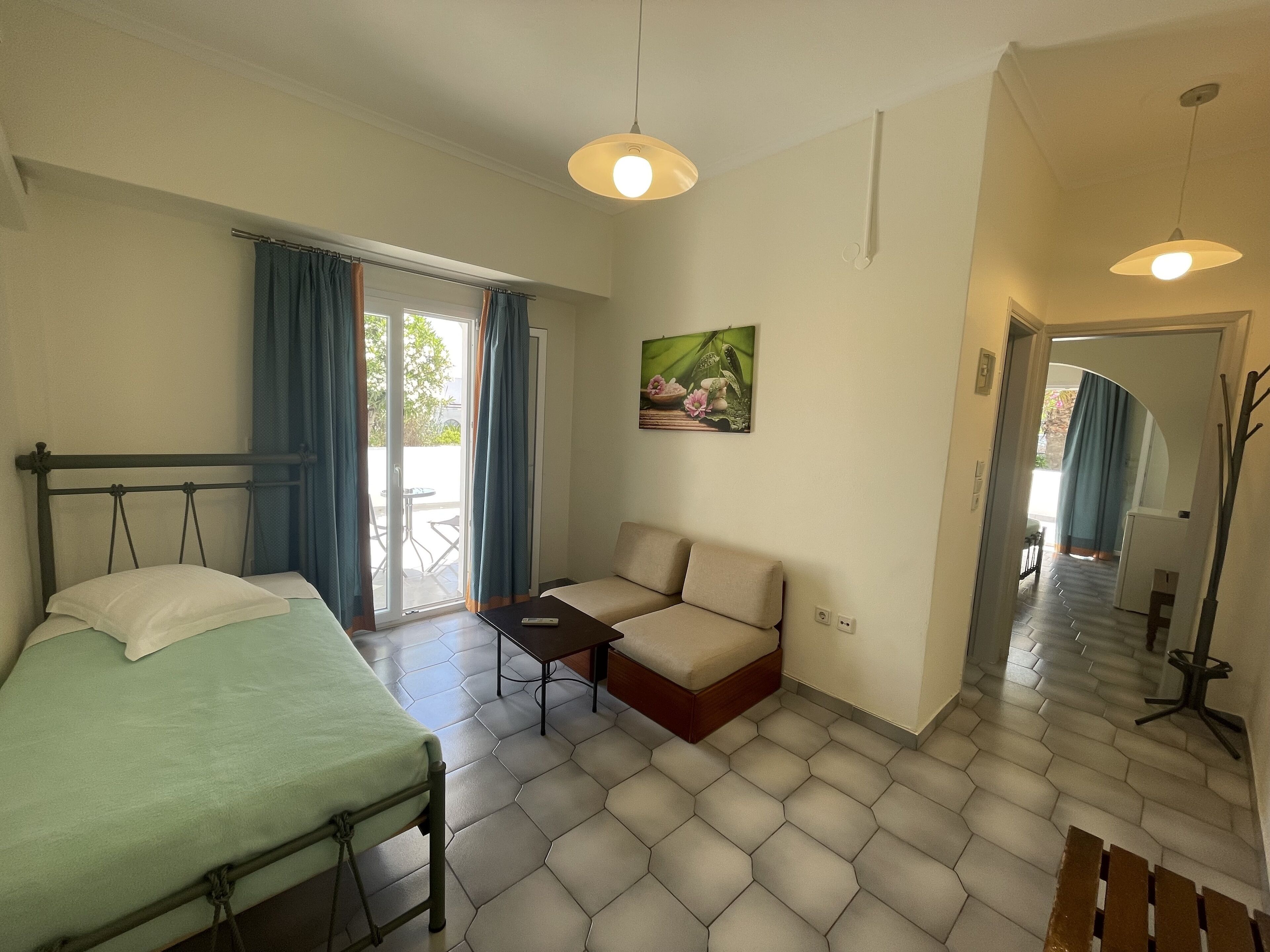 A room with a bed, a sofa, a small table, and a painting on the wall.