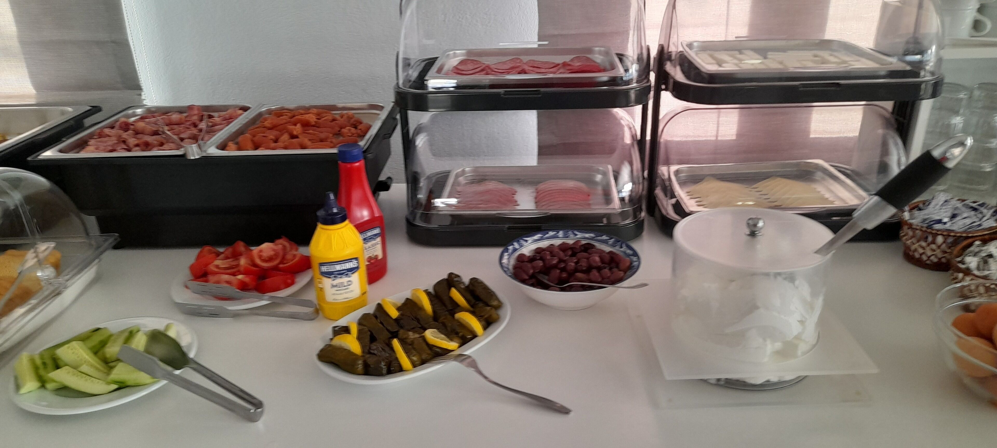 Un bufé con diferentes opciones de comida, incluyendo carnes, vegetales y salsas.