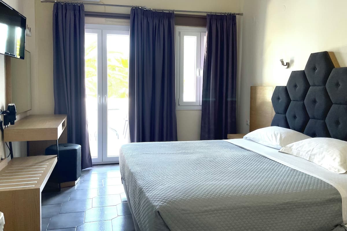 A hotel room with a bed, a desk, a chair, and a TV.