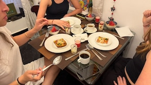 Ein Esstisch mit Pizza, Kaffee und Obstschalen.