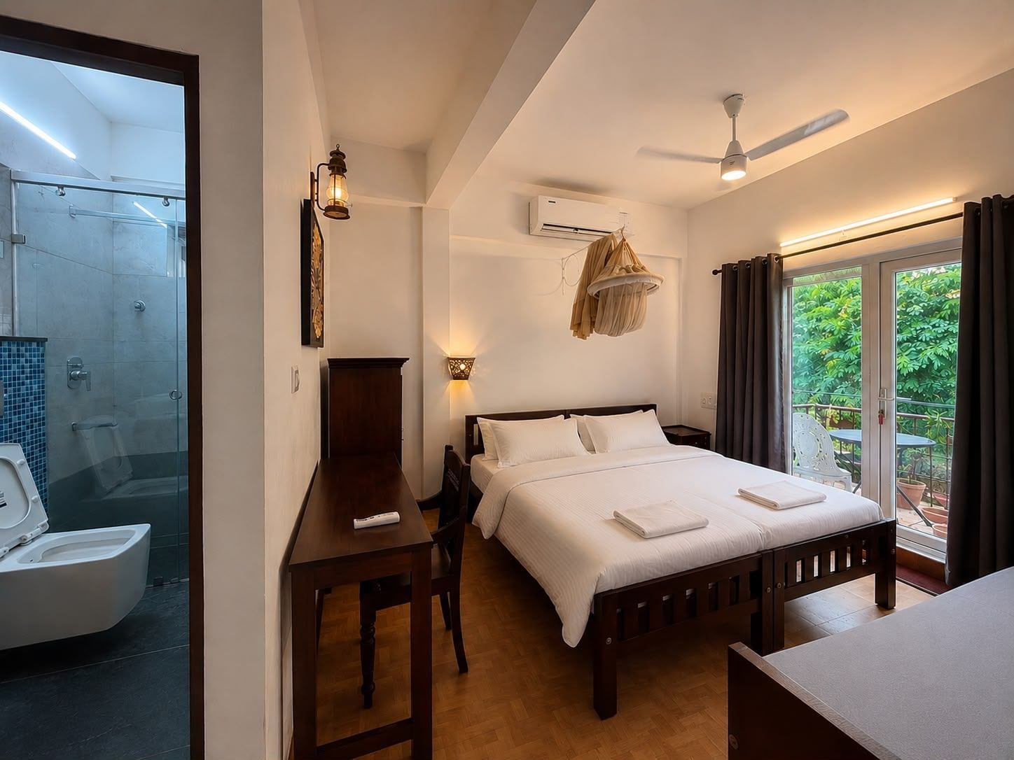 A hotel room with a bed, a desk, a chair, a shower, and a balcony with curtains.
