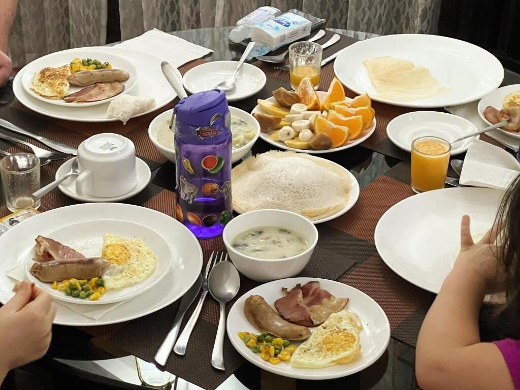 Un bufé de desayuno con diversos platos, como huevos, salchichas y frutas.