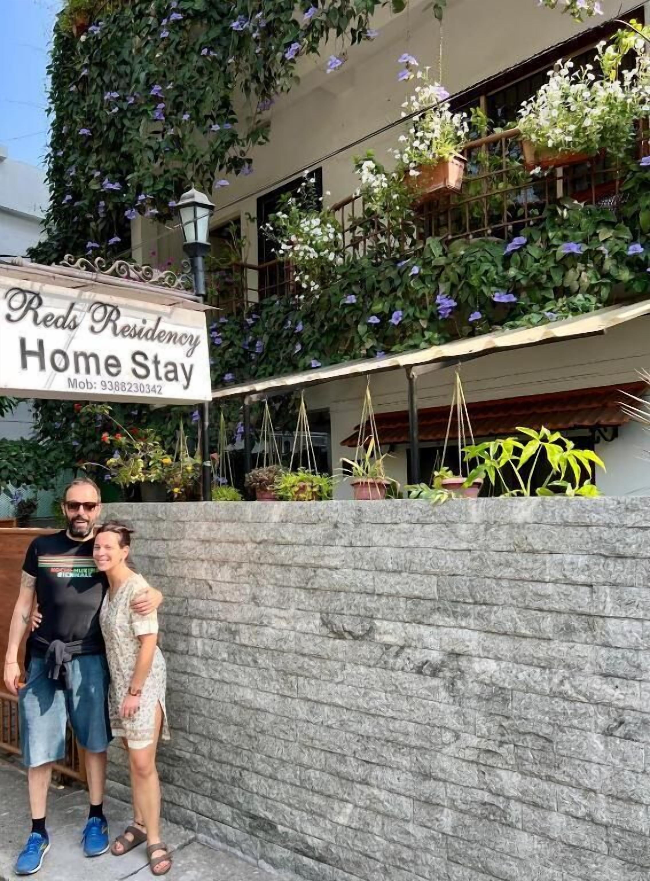 Placa indicando 'Reds Residency Home Stay' com um número de contato.
